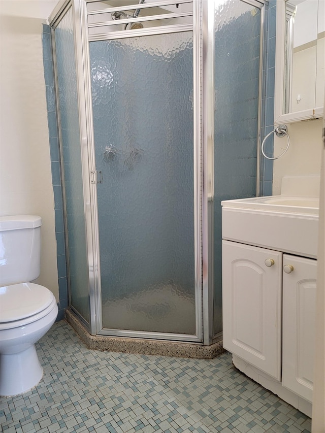 bathroom featuring tile patterned flooring, vanity, toilet, and a shower with door