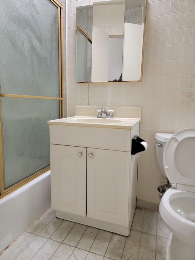 full bathroom featuring vanity, enclosed tub / shower combo, tile walls, and toilet