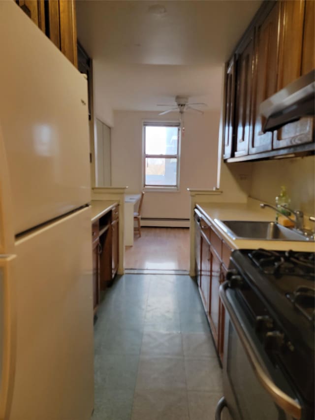 kitchen featuring black gas range, a baseboard heating unit, sink, ceiling fan, and white fridge