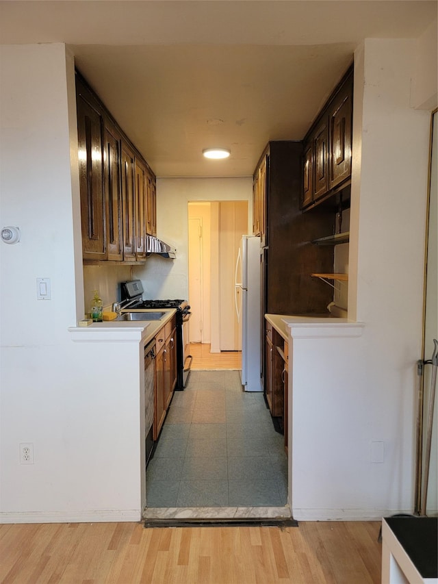 kitchen featuring white fridge, black range with gas cooktop, and ventilation hood