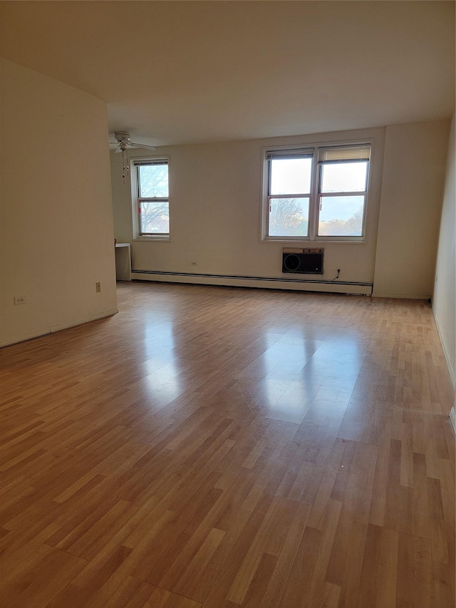 spare room with light wood-type flooring, a baseboard radiator, ceiling fan, and a healthy amount of sunlight