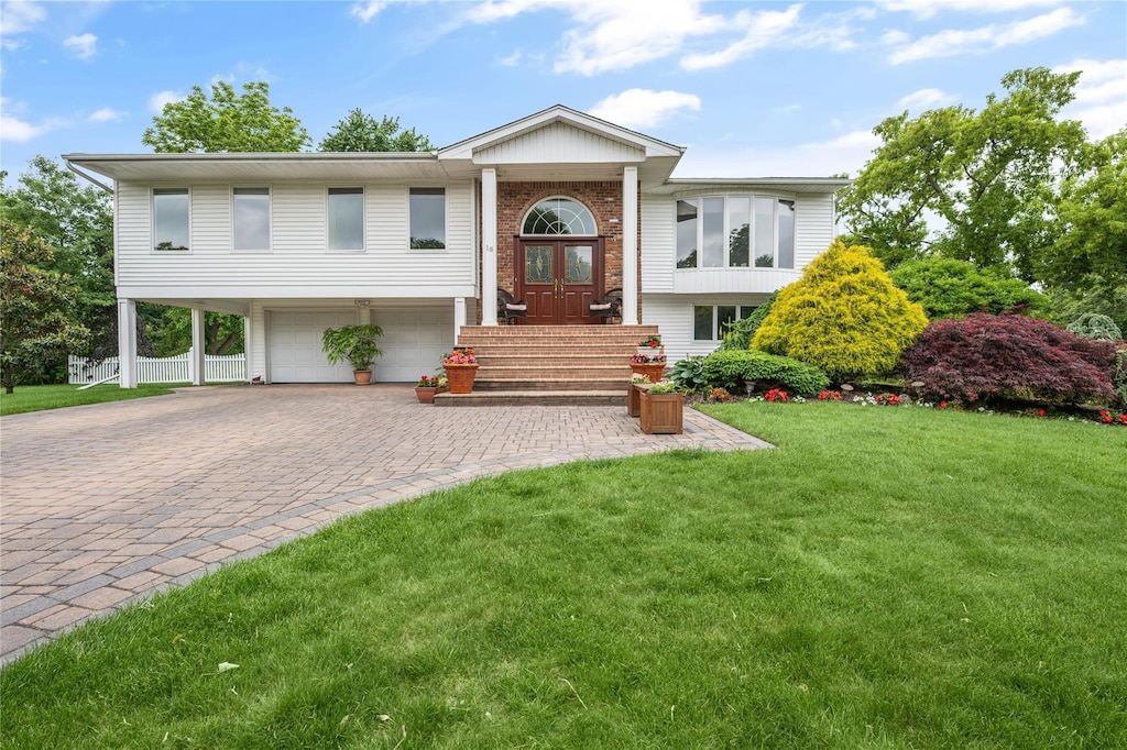 raised ranch featuring french doors, a front yard, and a garage