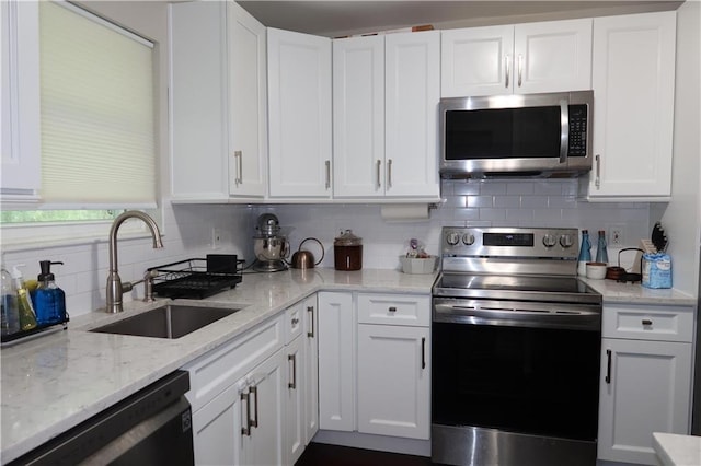 kitchen with tasteful backsplash, light stone counters, stainless steel appliances, sink, and white cabinets