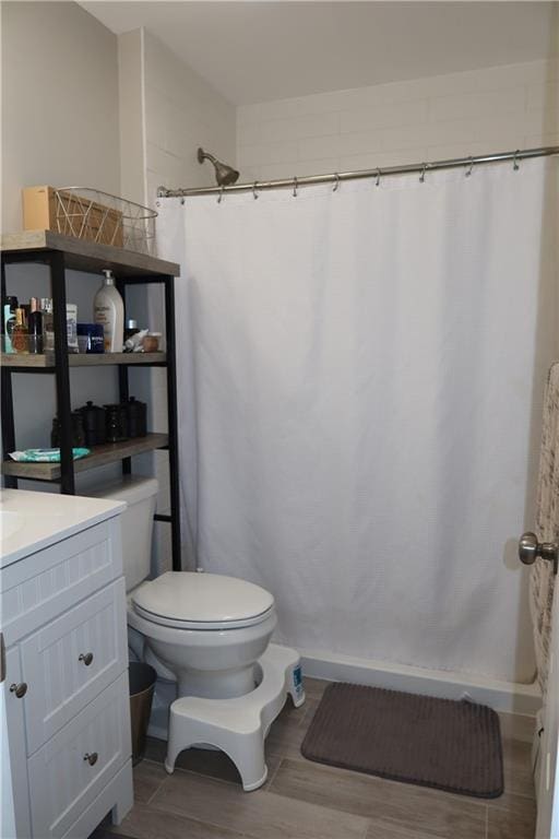 bathroom with a shower with shower curtain, vanity, hardwood / wood-style flooring, and toilet