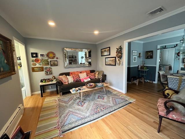 living room with baseboard heating, crown molding, and light wood-type flooring