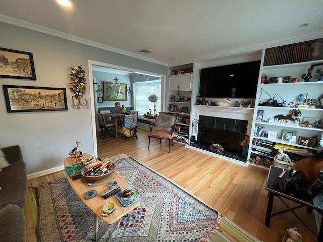 living room featuring a tile fireplace, hardwood / wood-style floors, and ornamental molding