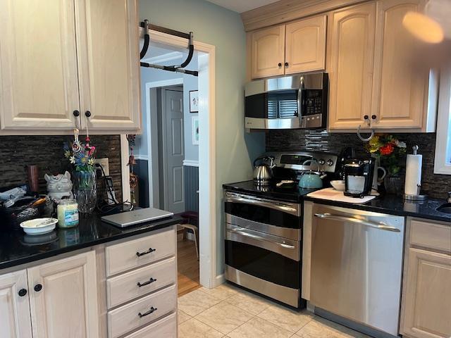 kitchen with decorative backsplash, light tile patterned flooring, and stainless steel appliances