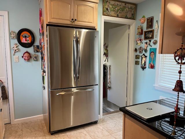 kitchen featuring stainless steel fridge, light tile patterned flooring, and light brown cabinetry