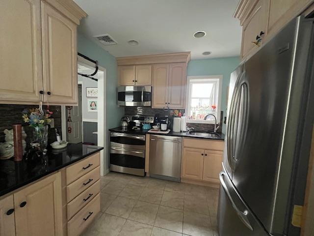 kitchen featuring light brown cabinetry, decorative backsplash, sink, and stainless steel appliances