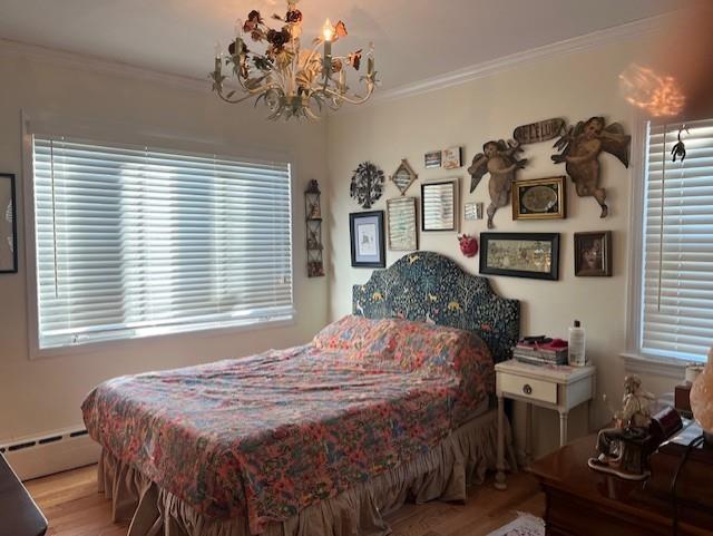 bedroom with baseboard heating, crown molding, a chandelier, and light wood-type flooring