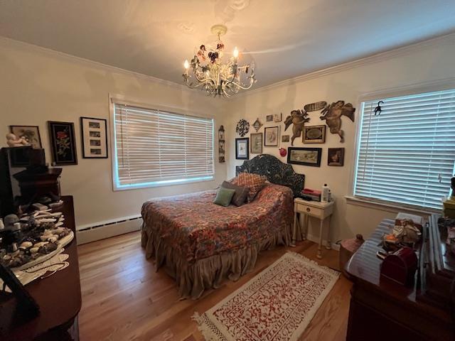 bedroom with hardwood / wood-style flooring, ornamental molding, baseboard heating, and a chandelier