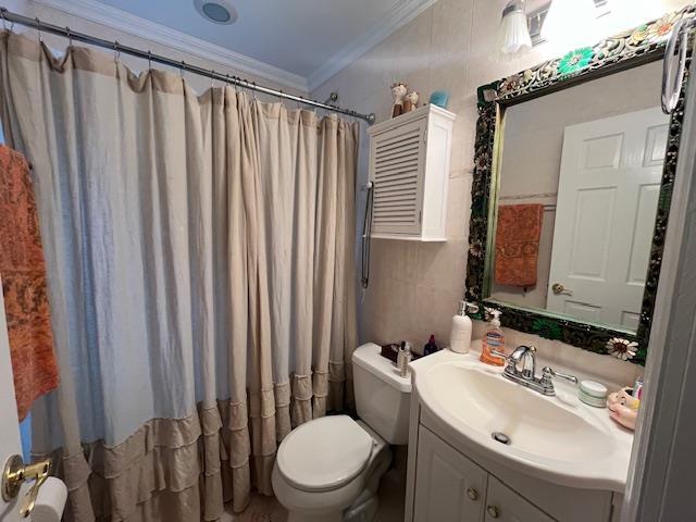 bathroom with walk in shower, crown molding, toilet, vanity, and tile walls