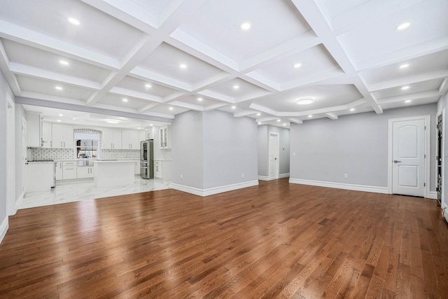 unfurnished living room with coffered ceiling, beam ceiling, and light hardwood / wood-style flooring