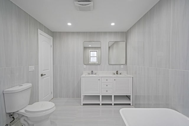 bathroom featuring vanity, a bathing tub, tile patterned floors, toilet, and tile walls