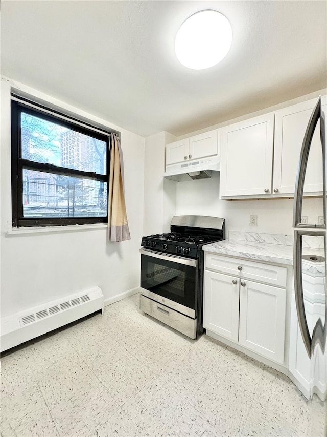 kitchen featuring stainless steel gas range oven, white cabinetry, fridge, and a baseboard radiator