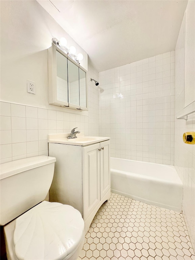 full bathroom featuring tile patterned flooring, toilet, vanity, tile walls, and tiled shower / bath