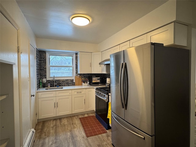 kitchen featuring gas stove, white cabinetry, stainless steel refrigerator, and sink