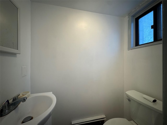 bathroom featuring toilet, a baseboard heating unit, and sink