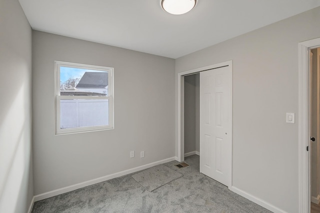 unfurnished bedroom with light carpet and a closet