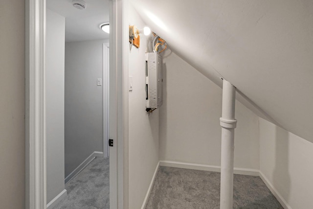 corridor featuring electric panel, light colored carpet, and vaulted ceiling