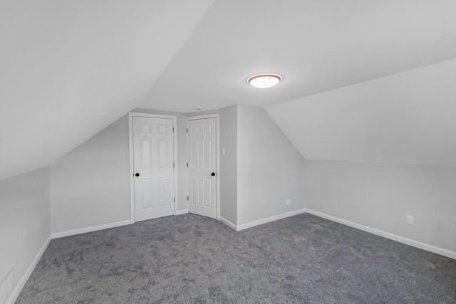 bonus room with vaulted ceiling and dark colored carpet