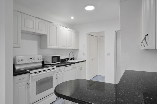 kitchen featuring white appliances, light tile patterned floors, sink, and white cabinets