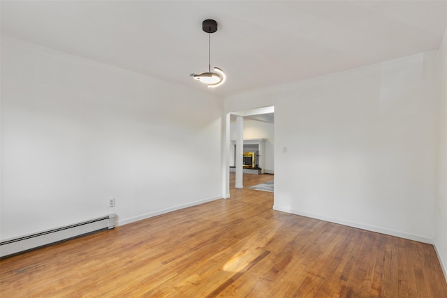 unfurnished room with a fireplace, hardwood / wood-style floors, and a baseboard radiator