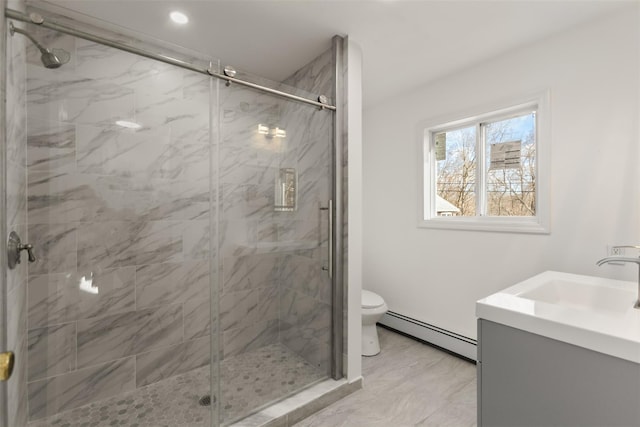 bathroom featuring vanity, toilet, a shower with door, and a baseboard heating unit