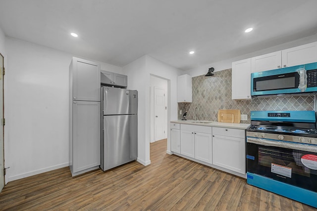 kitchen with sink, decorative backsplash, dark hardwood / wood-style floors, white cabinetry, and stainless steel appliances