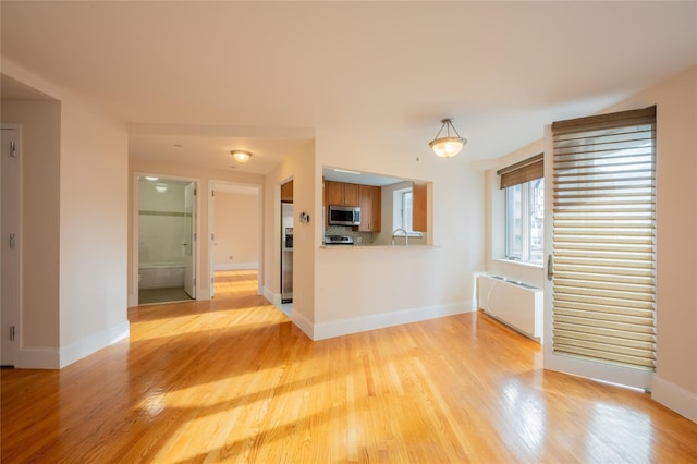 interior space with kitchen peninsula, tasteful backsplash, stainless steel appliances, sink, and light hardwood / wood-style floors