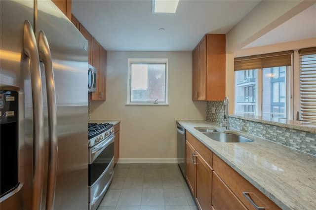 kitchen with backsplash, light stone counters, sink, and stainless steel appliances