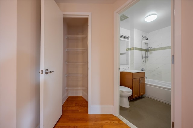 full bathroom featuring hardwood / wood-style floors, vanity, toilet, and tiled shower / bath