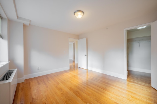 unfurnished bedroom featuring a walk in closet, light wood-type flooring, and a closet