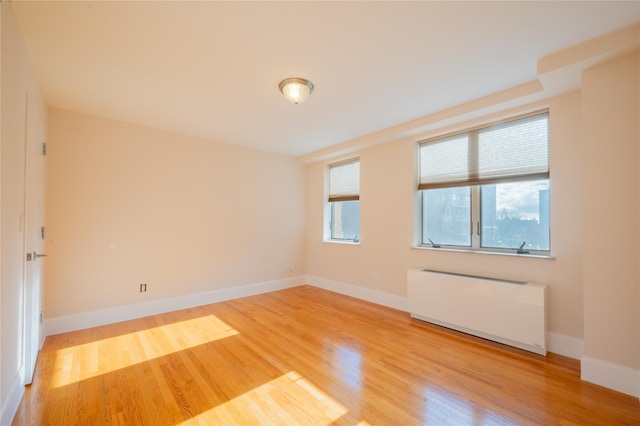 unfurnished room featuring hardwood / wood-style flooring and radiator