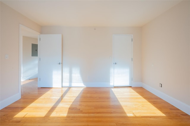 unfurnished room with electric panel and light hardwood / wood-style floors