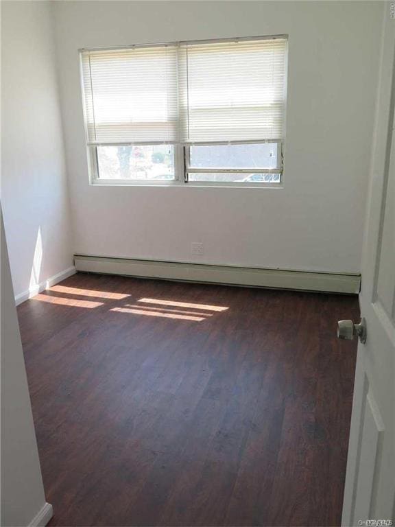 spare room with dark hardwood / wood-style floors and baseboard heating