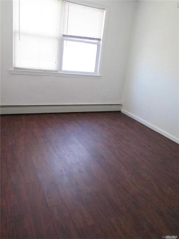 unfurnished room featuring dark hardwood / wood-style flooring and baseboard heating