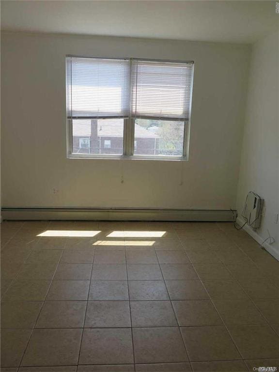 tiled empty room with baseboard heating and a healthy amount of sunlight