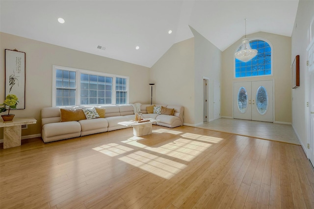 living room featuring french doors, high vaulted ceiling, a notable chandelier, and light hardwood / wood-style flooring