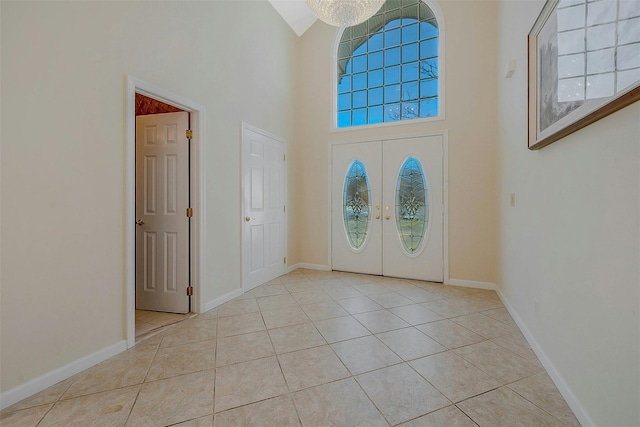 entrance foyer with french doors, a towering ceiling, and light tile patterned floors