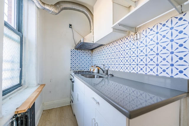 kitchen with white cabinets, backsplash, light hardwood / wood-style flooring, and sink