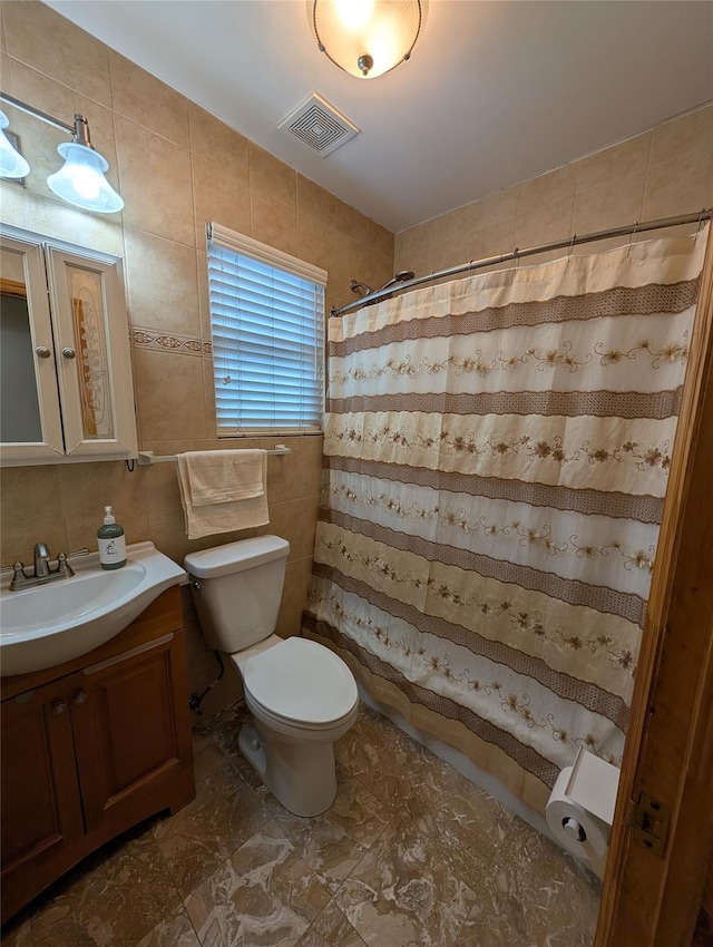 bathroom with vanity, toilet, tile walls, and walk in shower