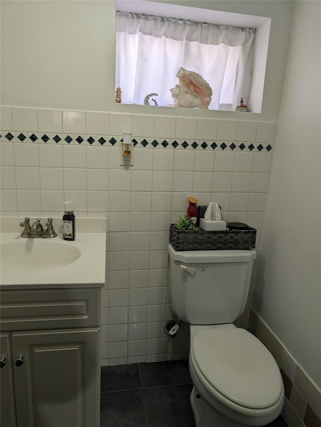 bathroom featuring tile patterned floors, vanity, toilet, and tile walls