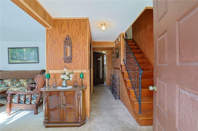 carpeted foyer with crown molding and wooden walls