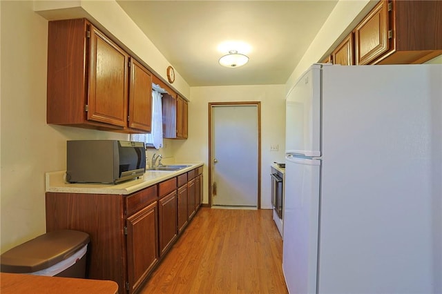 kitchen with white refrigerator, sink, range, and light hardwood / wood-style flooring