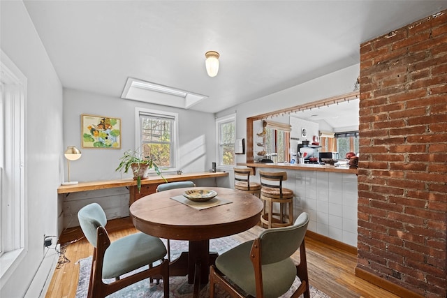 dining space with hardwood / wood-style floors and a skylight