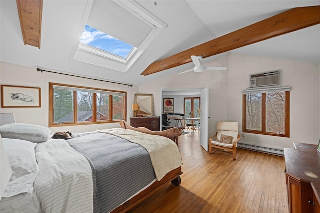 bedroom featuring an AC wall unit, vaulted ceiling with skylight, baseboard heating, hardwood / wood-style flooring, and ceiling fan