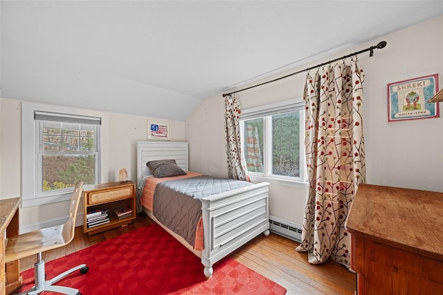 bedroom featuring multiple windows, a baseboard heating unit, lofted ceiling, and light wood-type flooring