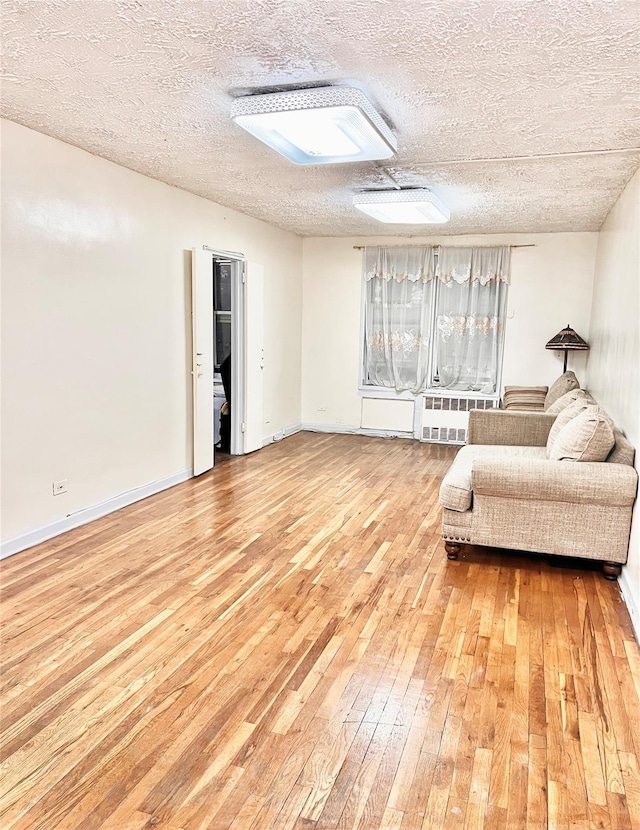 unfurnished room with a textured ceiling, light hardwood / wood-style flooring, and radiator