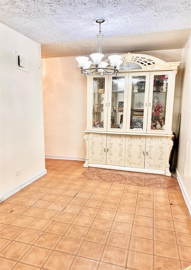 unfurnished dining area featuring light tile patterned floors, a textured ceiling, and an inviting chandelier